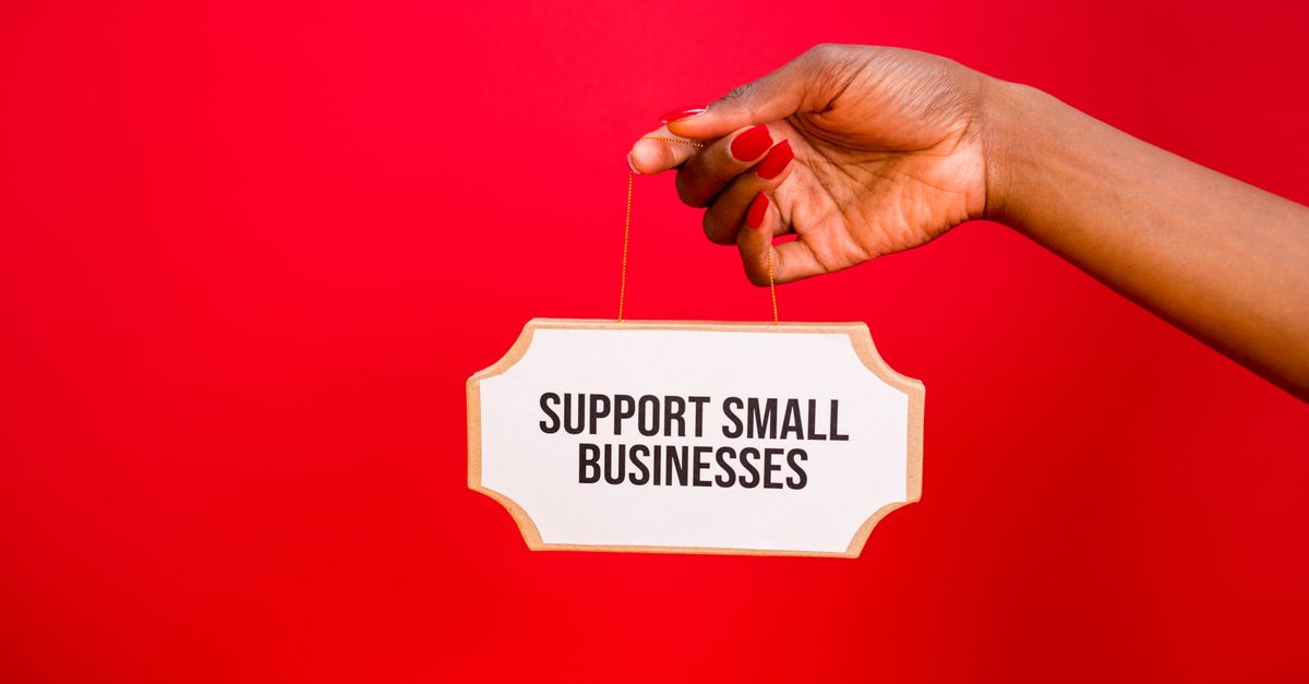 A hand holds a sign that reads 'Support Small Businesses' against a vibrant red background.